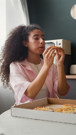 woman enjoying a slice of pizza at home
