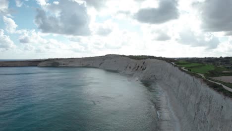 Aerial-View-Over-Ras-il--Fenek-Limestone-Cliff-Side,-With-Tropical-Turquoise-Water,-Blue-Sky-And-Fluffy-White-Clouds,-Malta