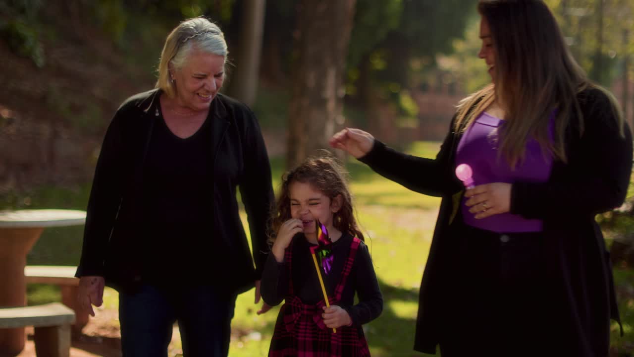 Three generations enjoying a sunny day in the park with bubbles and pinwheels