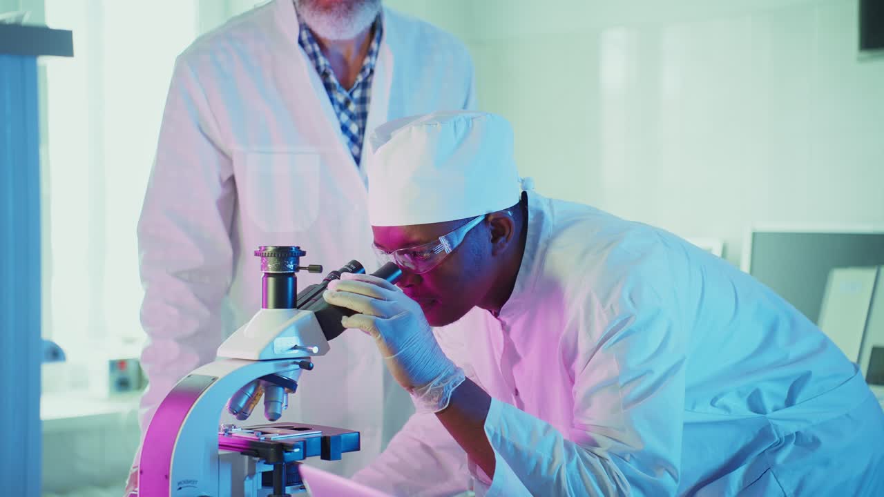 Diverse Scientists Collaborating and Using Microscope in Modern Laboratory
