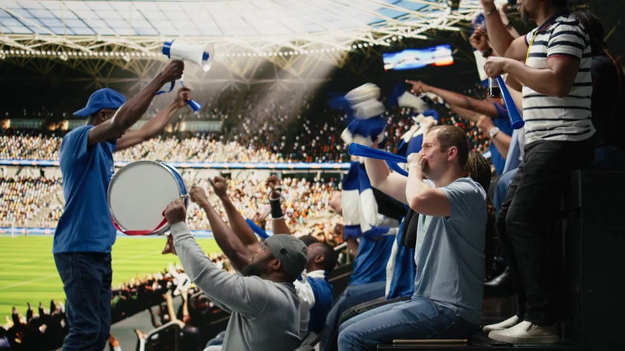 Hinchas enérgicos tocando un tambor de percusión y soplando vuvuzelas.