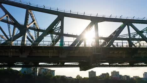 silhouette of a cyclist travelling across a large bridge with the sun behind