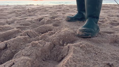 un pescador trabajando en su línea en una playa de arena con una impresionante puesta de sol en la distancia