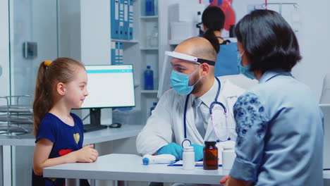 Cheerful-pediatrician-smiling-at-little-girl