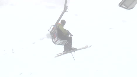 Ski lift ride in foggy snowy mountain