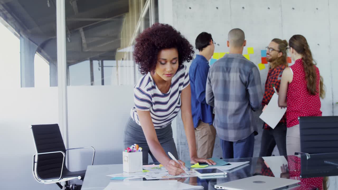 mulher a trabalhar à mesa com os seus colegas no fundo 4k
