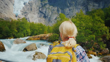 a woman traveler looks at the famous briksdal glacier in norway a back view