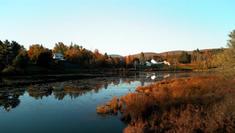 Aerial-push-through-trees-next-to-lake-in-the-Catskills,-brilliant-fall-foliage