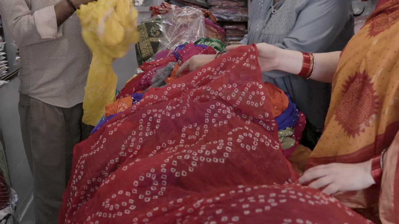 venditore di abbigliamento al dettaglio che mostra un diverso tipo di saree tradizionale indiano al cliente al negozio