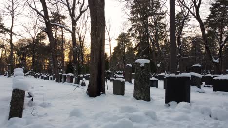 bunch of snow covered graves in a graveyard during the sunset