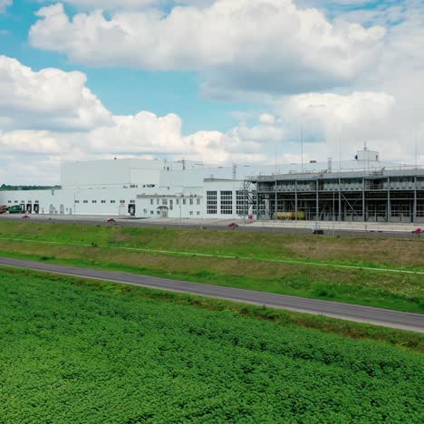 industrial zone in the countryside. factory construction near the highway on green nature background. modern manufacturing under the sky