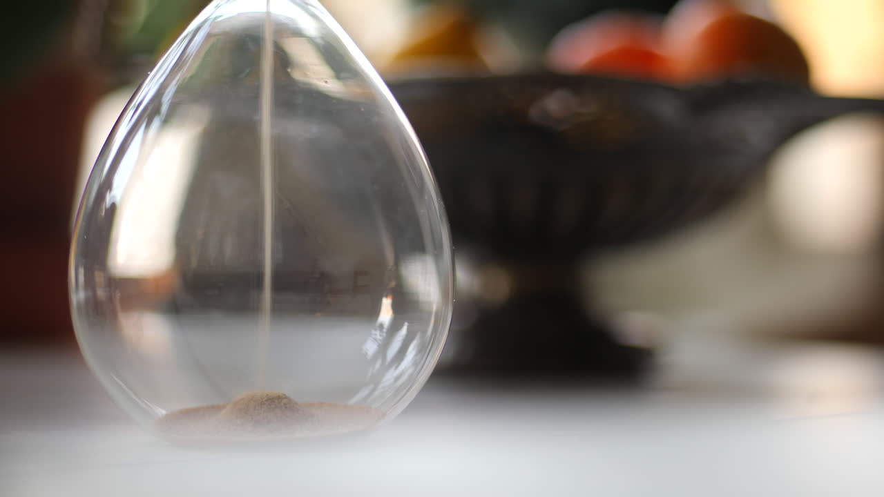 Hourglass sand falling in slow motion bokeh
