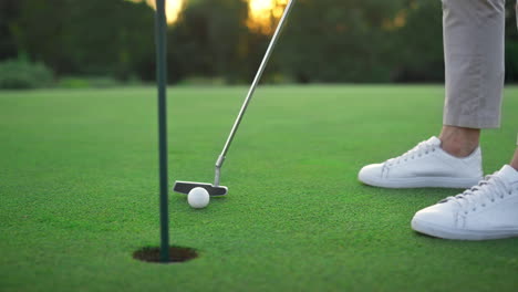 golf club hitting ball in hole green course. golfing player swing teeing putter.