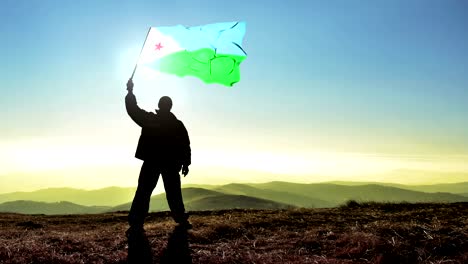 successful silhouette man winner waving djibouti flag on top of the mountain peak. cinemagraph loop background