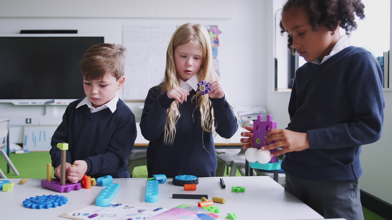 tres niños de escuela primaria trabajando juntos con bloques de construcción en un aula, vista delantera