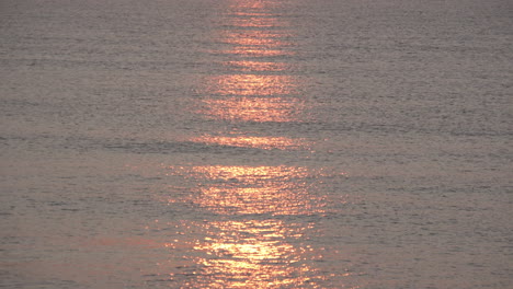 a stunning red and golden sunrise reflects on calm silvery waters as small waves roll in