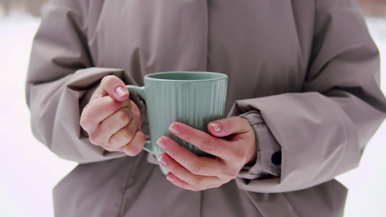 mujer sosteniendo una taza de bebida caliente en invierno