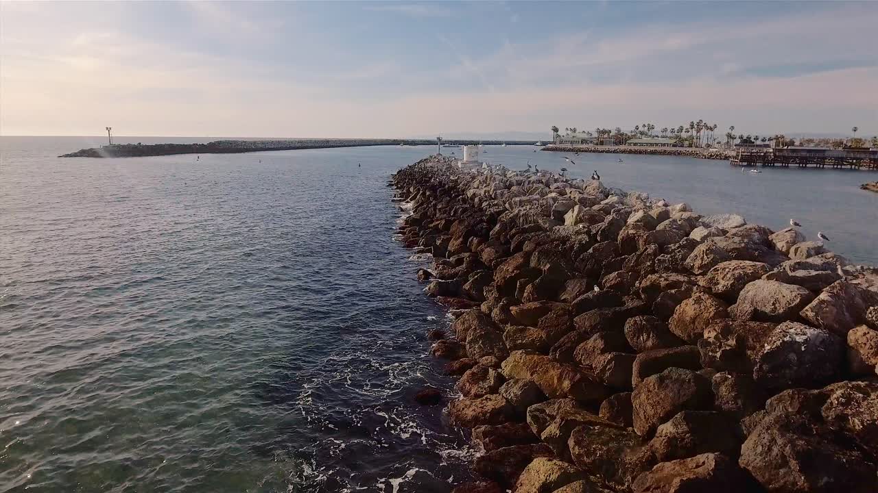 imágenes aéreas volando sobre las rocosas bermas rompen el agua en la playa de redondo, california