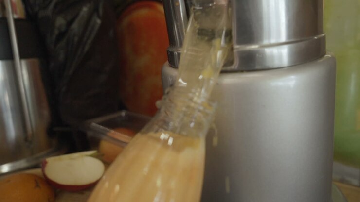 Close up of Mans hand filling bottle with freshly squeezed orange juice