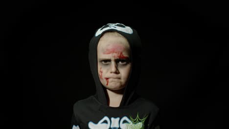 halloween, angry girl with blood makeup on face. kid dressed as scary skeleton, posing, making faces