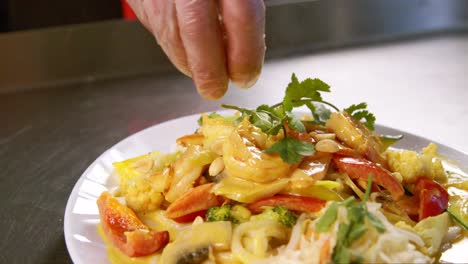 chinese chef adorning dishes with crunchy peanuts