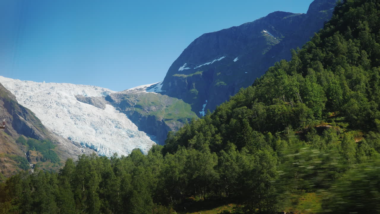 проезжая по живописным местам норвегии за окном видны высокие горы и большое озеро