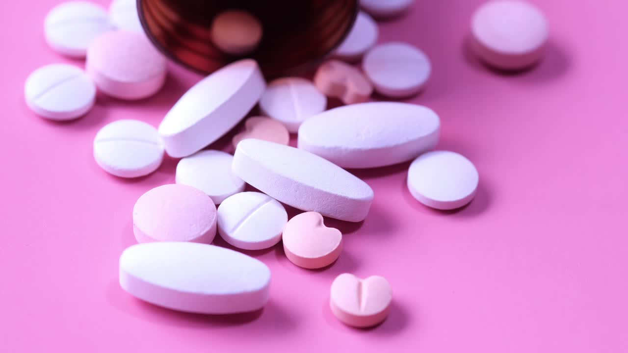 분홍색 표면에 컨테이너에서 흘러 내린 다양한 약