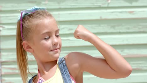 Portrait-of-happy-caucasian-girl-pumping-arm-over-beach-house