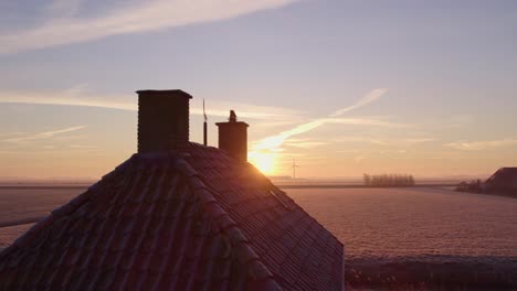 sun reveals behind small house near dutch windmill, aerial