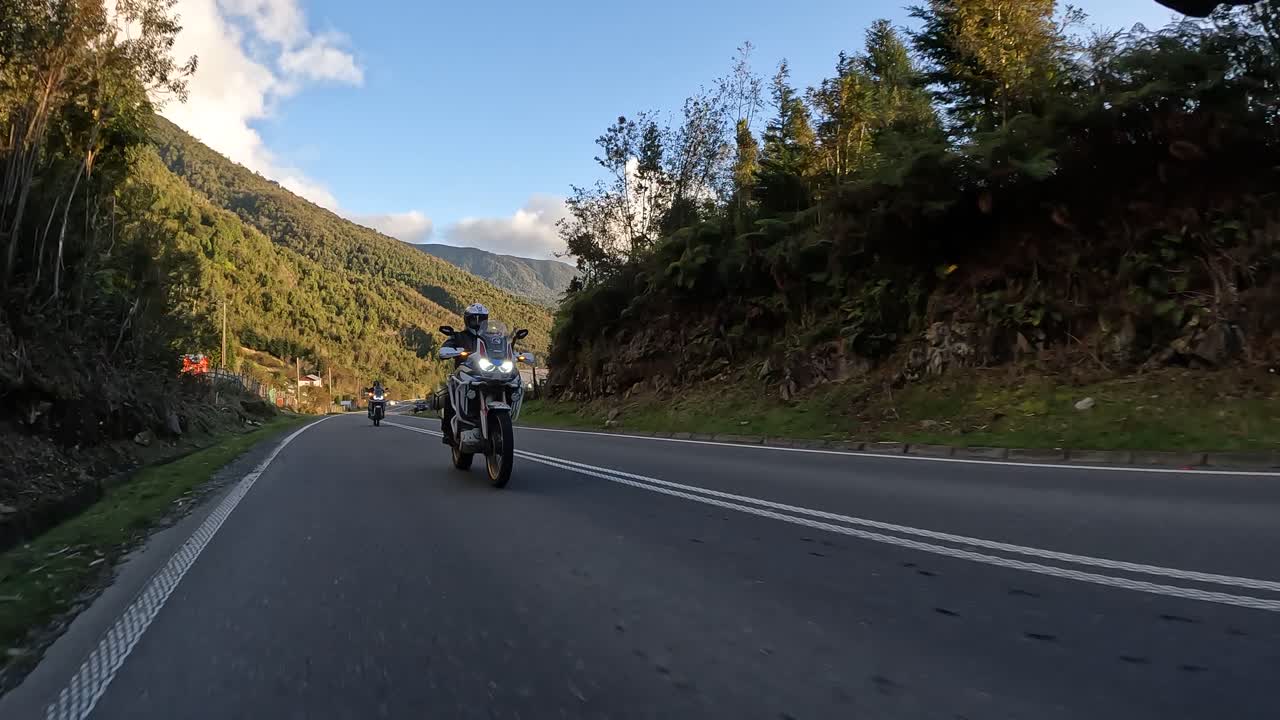 Biker on adventure motorcycle riding on rural asphalt road. Northern Chilean Patagonia. Golden hour
