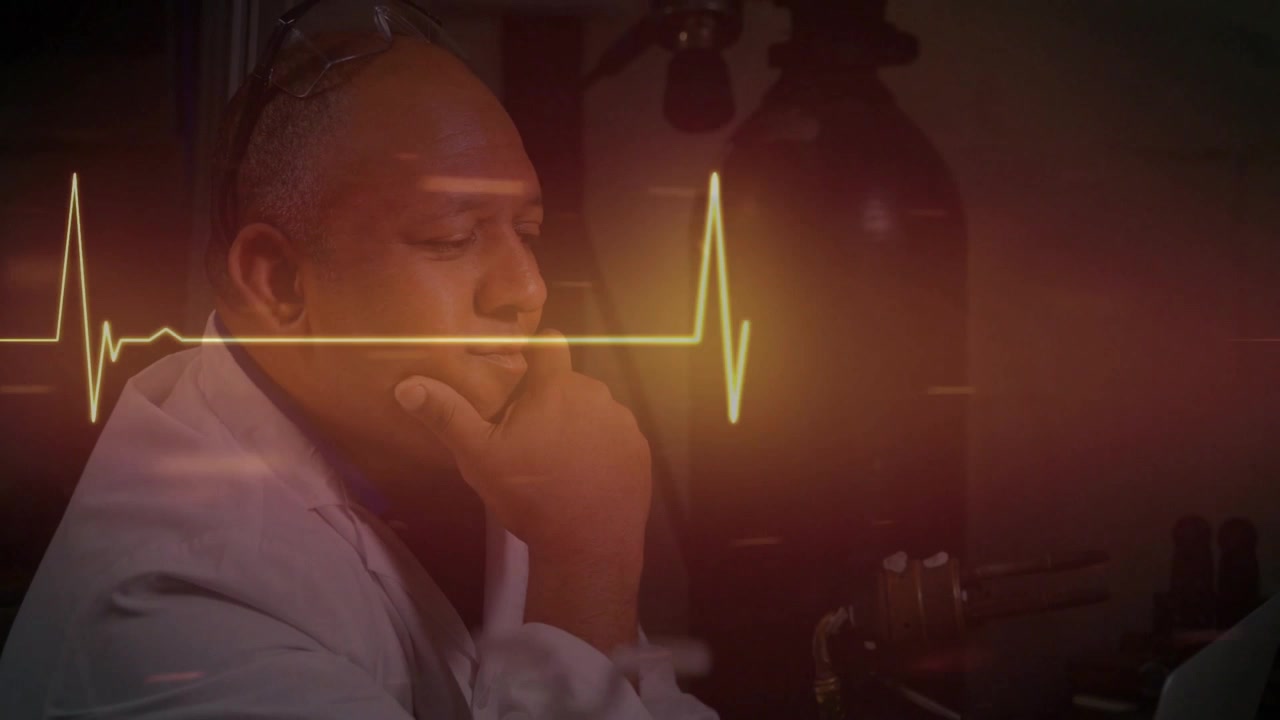 Pulsing ECG initiating male lab tech clasping hands, resting chin, scanning bench gauges and tanks