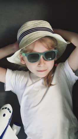 adorable toothless little girl in sunglasses smiles looking in camera. cute shy preschooler with accessories ready for trip upper close view