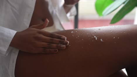 mujer aplicando exfoliante de coco a la pierna