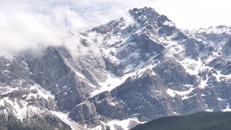 majestuosa vista del pico zugspitze cubierto de nieve en eibsee, grainau, alemania, nubes a la deriva