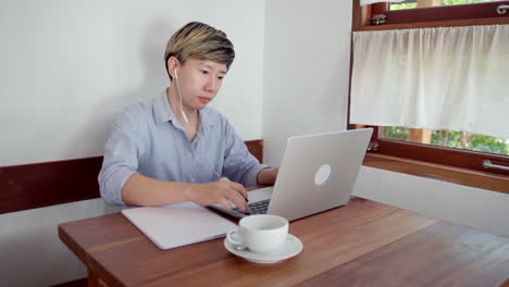 adult short hair woman sit and take note for online meeting with laptop in cafe during daytime