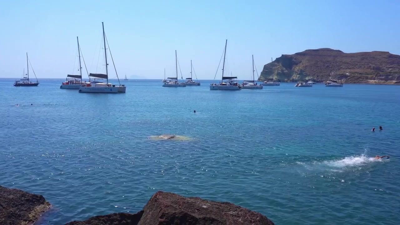 Persona che si tuffa nell'acqua turchese a Santorini, Grecia.