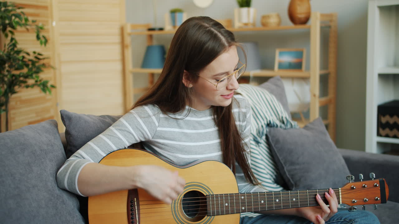 женщина играет на акустической гитаре дома