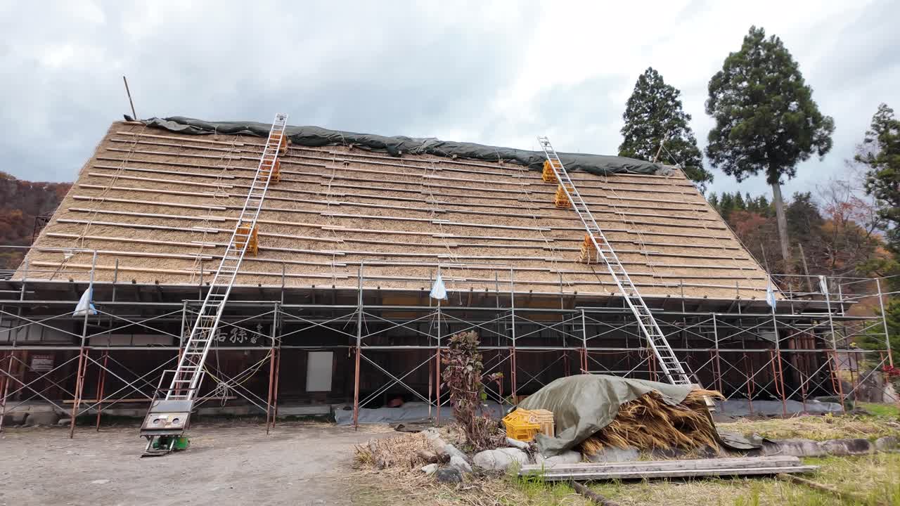 Stillaser støtter arbeidere som restaurerer et rustikt Gasshō-zukuri-stil tak i Shirakawago. Panorer til venstre