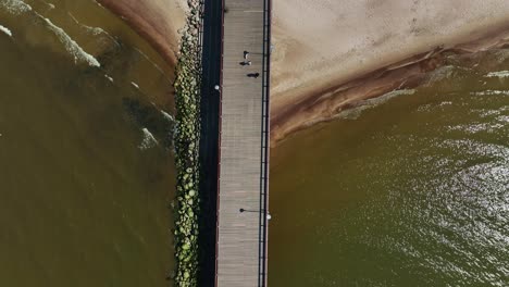 Aerial-view-a-bridge-standing-on-the-beach-of-Palanga,-which-goes-to-the-Baltic-Sea