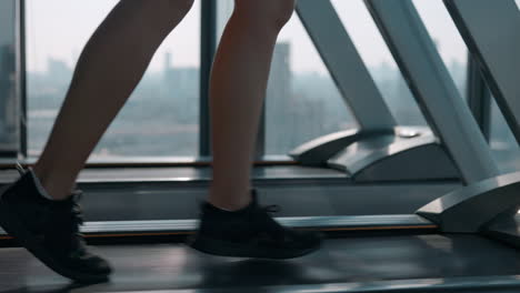 person running on a treadmill in a gym with a city view