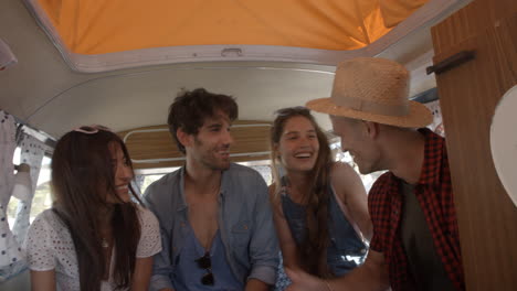 four friends on a road trip talk in the back of a camper van