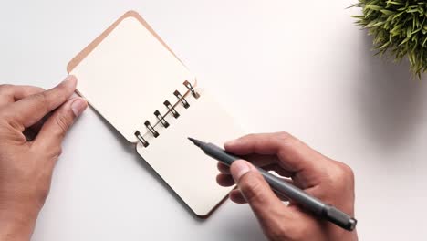 person writing in a spiral notebook