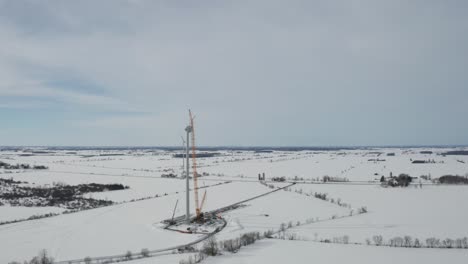 Impresionante-Vista-Aérea-De-Invierno-Del-Sitio-De-Construcción-De-Energía-Eólica-Cubierto-De-Espectáculo-Con-Grúa-Contra-Torre