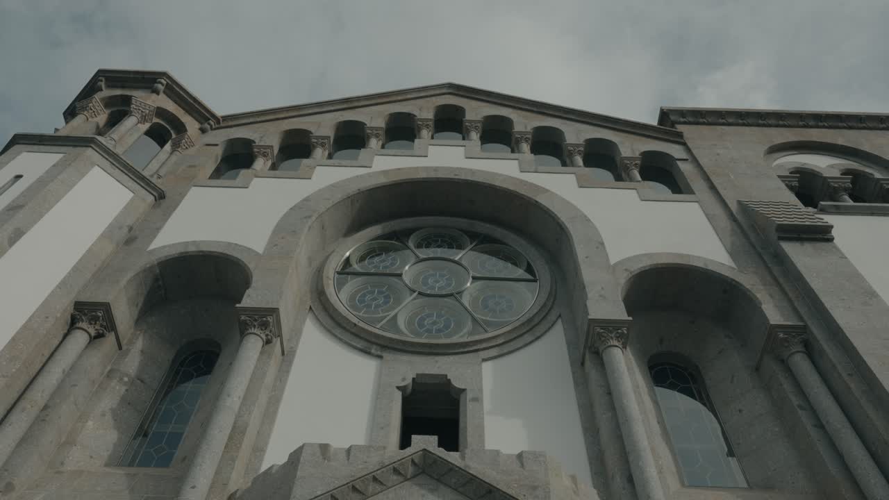 Vista en ángulo bajo de la fachada de piedra ornamentada del santuario y el rosetón en Paços de Ferreira, Portugal