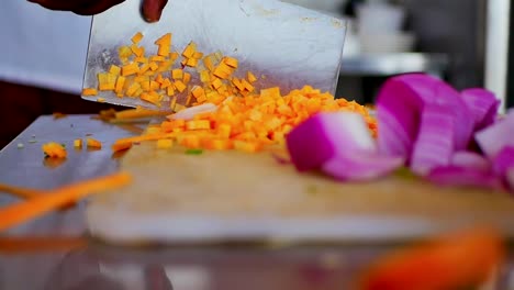 chef chopping carrots on a white chopping board