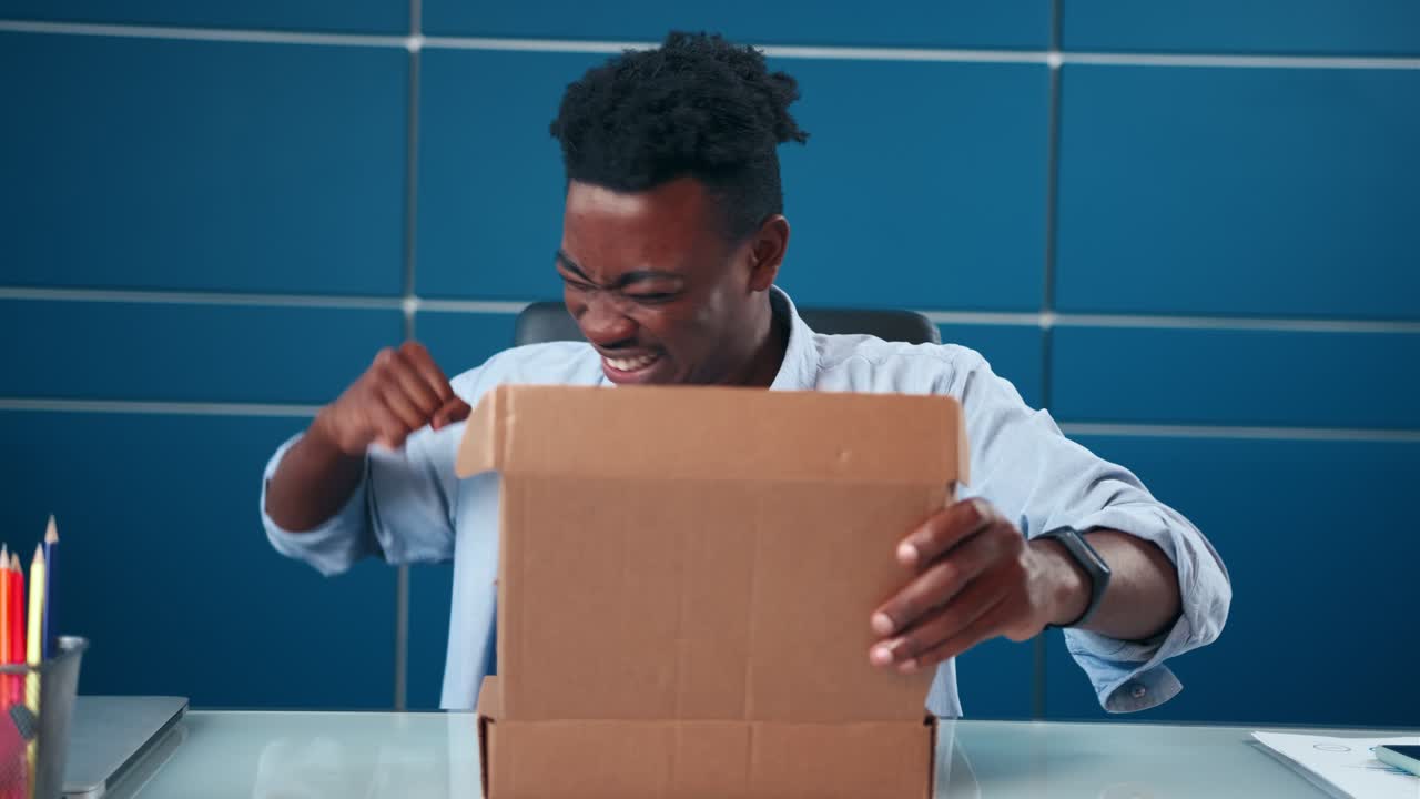 Excited african man receives parcel open box at home satisfied with great goods