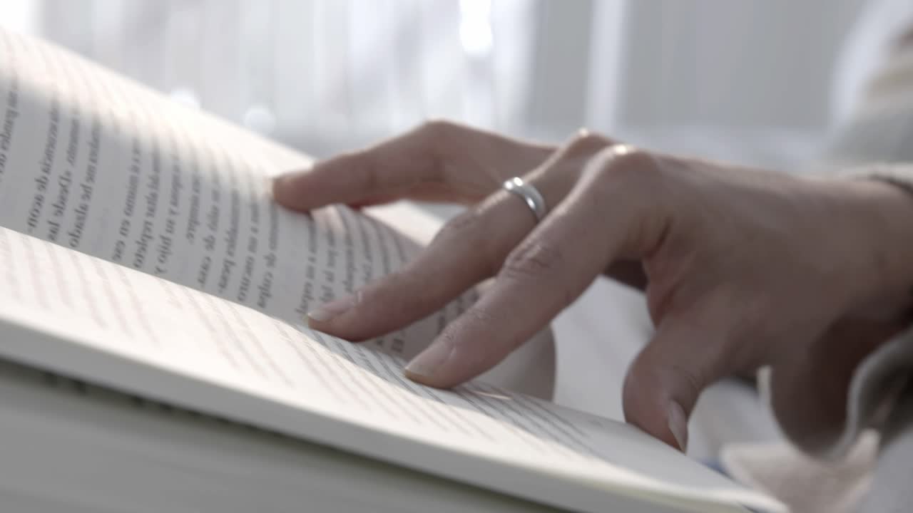 Close-up of Hand Turning Pages While Reading a Book