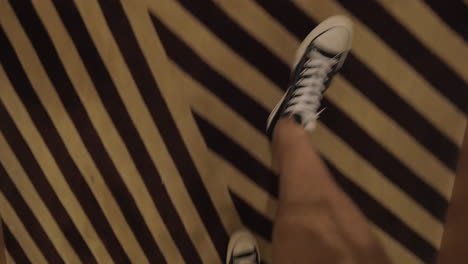 View-of-looking-down-at-man-legs-in-canvas-shoes-going-on-a-striped-carpet-in-the-hall-Hong-Kong-China