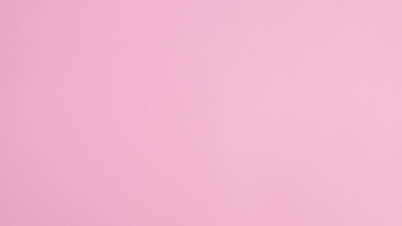 Summer beach bag, hat and accessories appear on pastel pink background. Stop motion flat lay