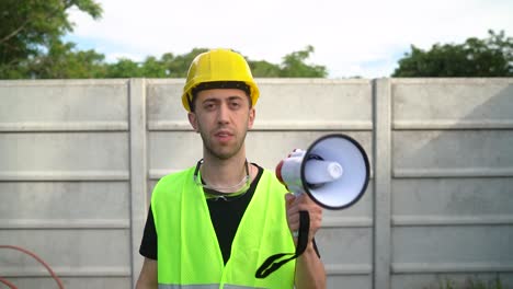 protesting - general labourer shouting in megaphone while raising arm